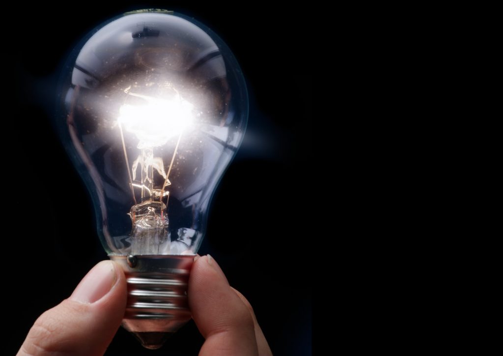 hand holding clear lightbulb in dark room