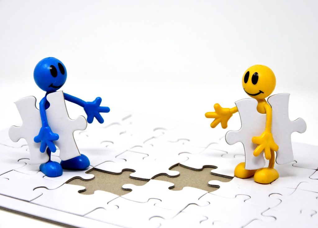 two smiley face stick figures putting together a puzzle
