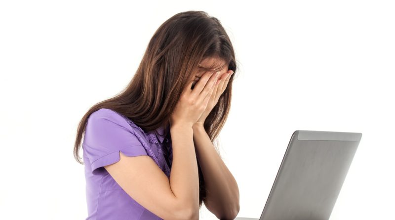 woman covering face at laptop
